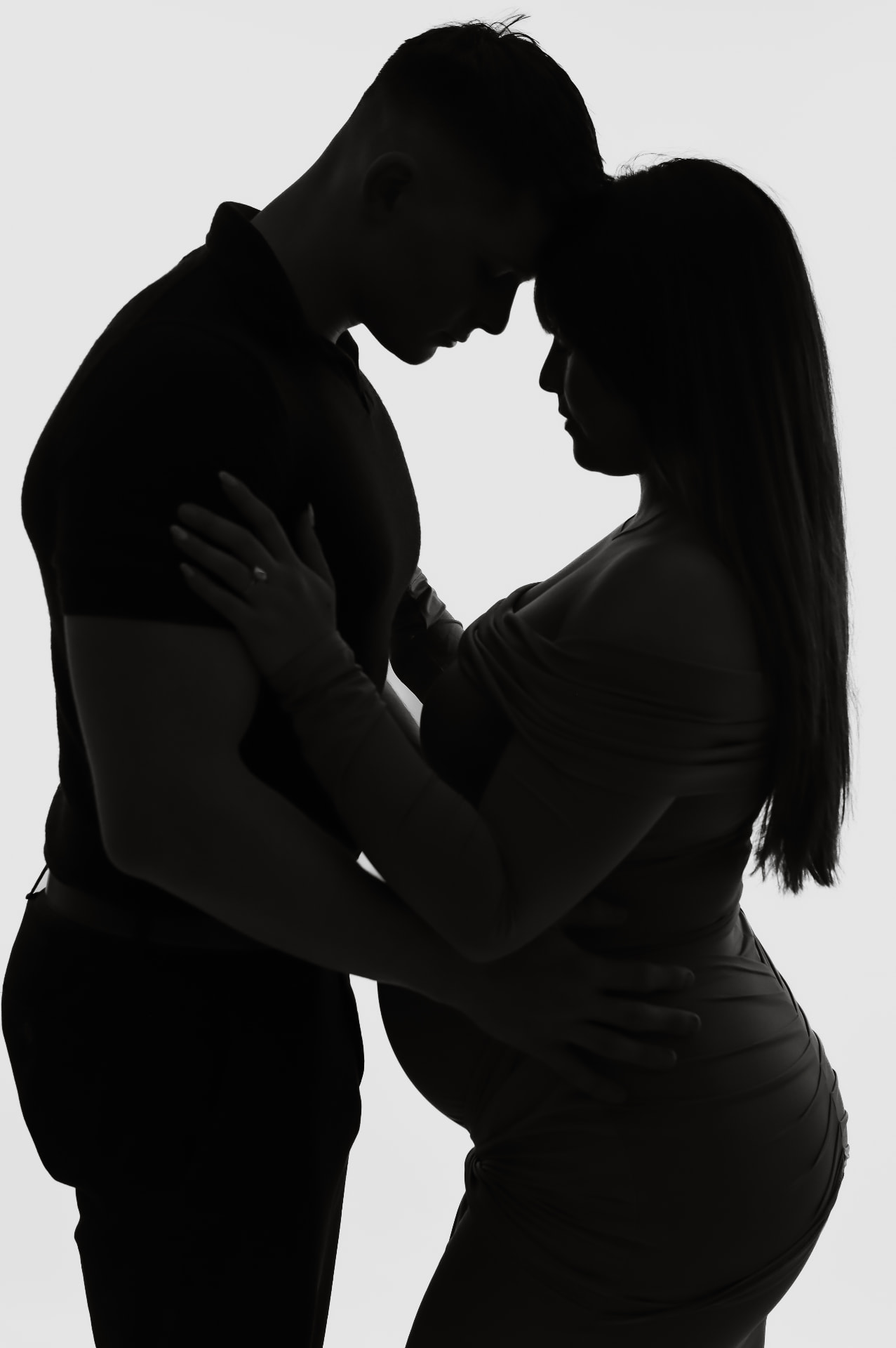 Silhouette studio portrait of expectant parents forehead to forehead