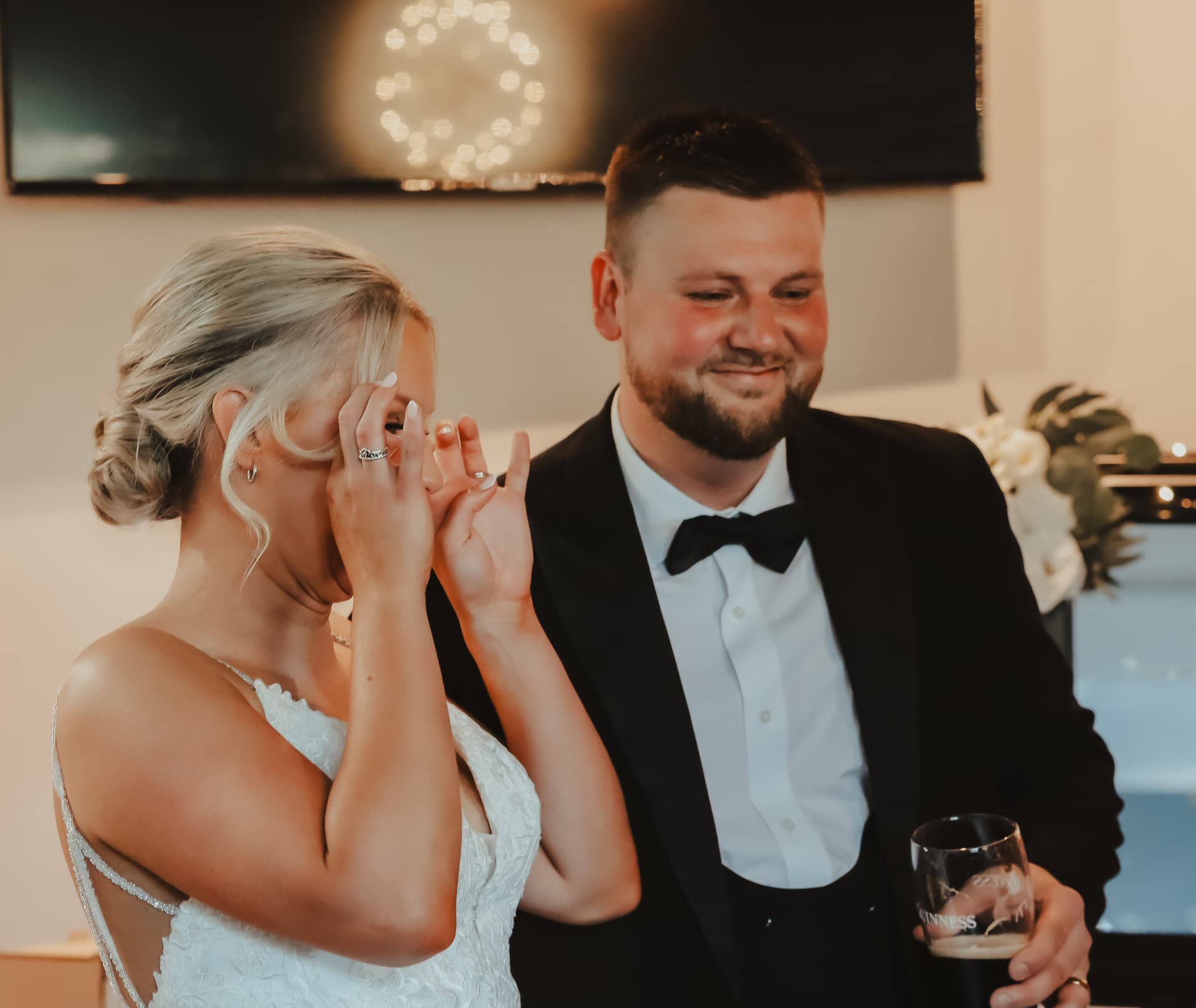 Bride wiping away happy tears beside her smiling groom during the speeches