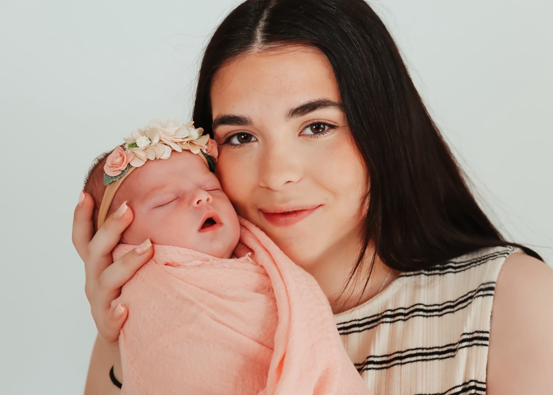 Mother gently holding her newborn baby wrapped in a soft pink blanket