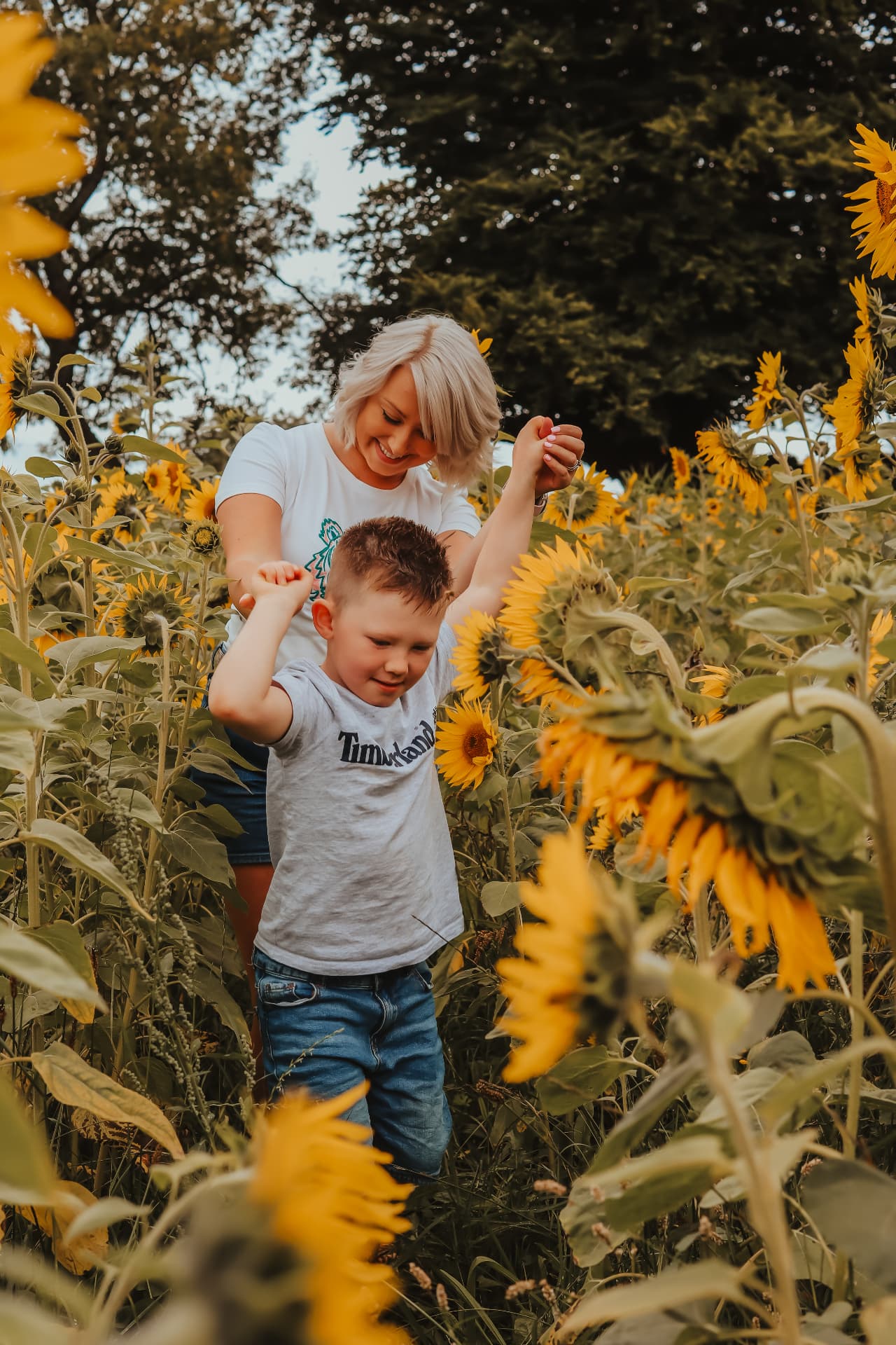 Mother dancing with her young son among the sunflowers