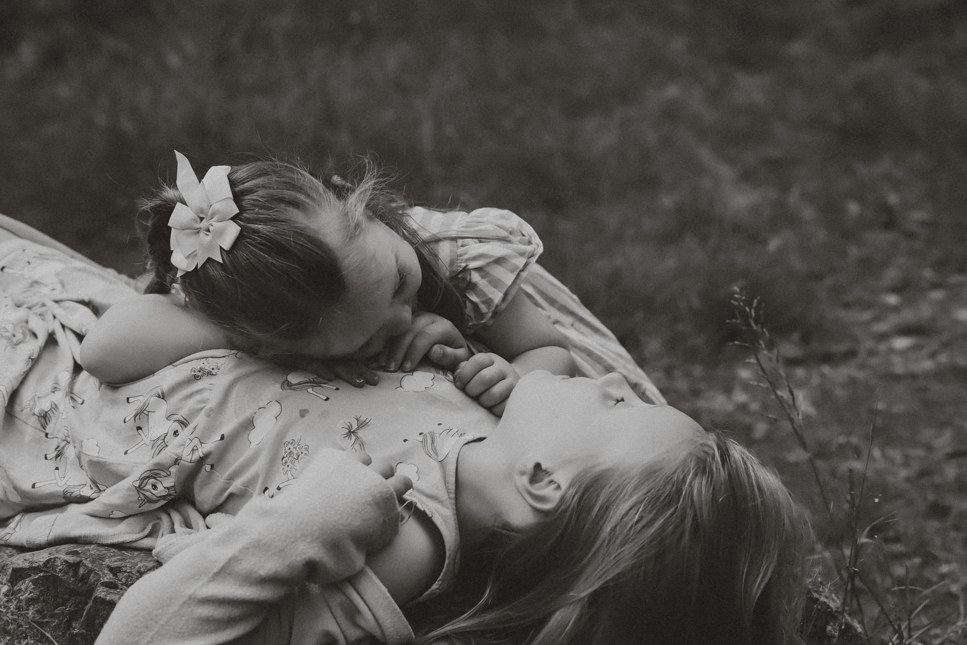 Black and white photograph of two sisters lying together in long grass